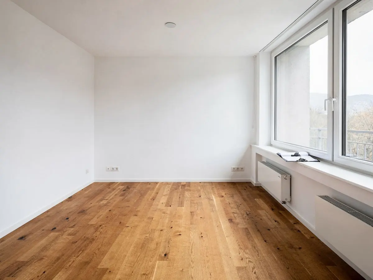 Symbolbild: leere, saubere Wohnung mit Parkett und grossen Fenstern